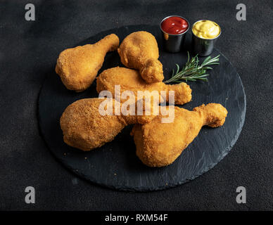 crispy fried chicken legs breaded golden color on black background Stock Photo