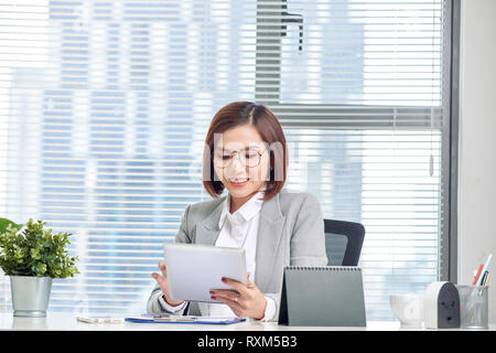 Asian businesswoman working with tablet computer at office desk. Stock Photo