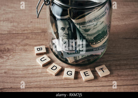 word budget made of wooden blocks and glass jar filled with dollar banknotes Stock Photo