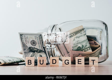 us dollars bill in glass jar and word budget made of wooden blocks Stock Photo