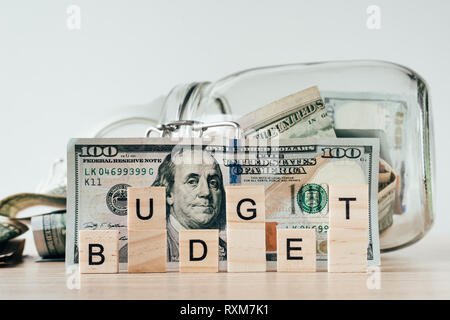 us dollars bill in glass jar and word budget made of wooden blocks Stock Photo