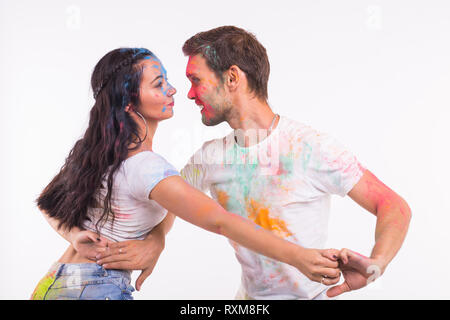 Holiday, social dance, holi and people concept - Happy couple having fun covered in paint and dancing bachata or kizomba on white background Stock Photo