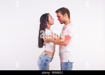 Holiday, social dance, holi and people concept - Happy couple having fun covered in paint and dancing bachata or kizomba on white background Stock Photo