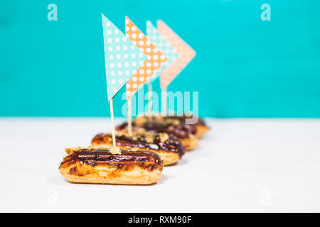 Food, desserts and bakery concept - traditional french eclairs with decorative flags on blue-white background Stock Photo