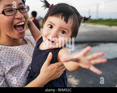 Little girl kid and mom have fun | Little child reach out and happy mom Stock Photo