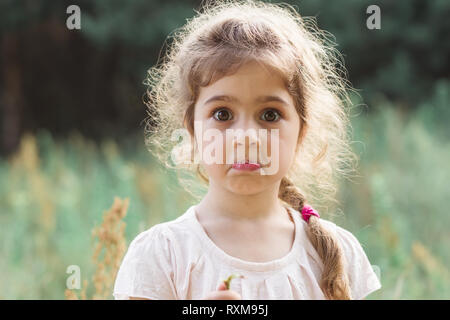 Close up Portrait of beautiful little Girl holding her head in amazement and surprised with something at summer day