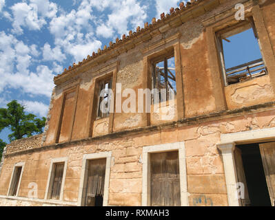 Old abandoned ruined building with many windows and no roof under sky with some clouds in day light. Stock Photo