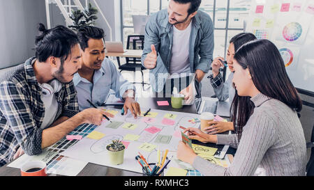 Creative director team lead thumbs up at brainstrom branding project with designer team at meeting table.discussion idea in creative office Stock Photo