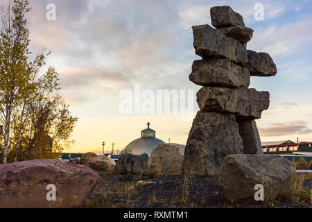 an Inukshuk and the Our Lady of Victory Church, Inuvik, Northwest Territories, Canada Stock Photo