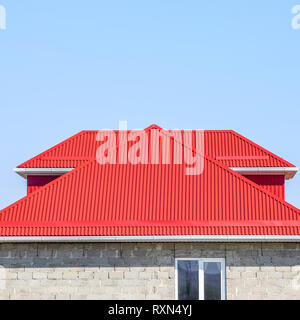 Red corrugated roof. House of cinder block. The house with plastic windows and a roof of corrugated sheet. Stock Photo