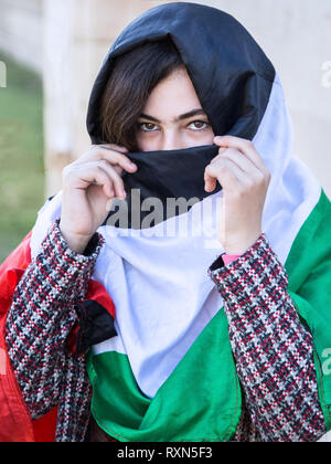 A portrait photo of Palestinian little girl masked with Palestinian flag, Gaza City Palestine. Stock Photo