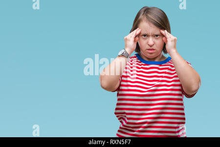 Young adult woman with down syndrome over isolated background with hand on head for pain in head because stress. Suffering migraine. Stock Photo