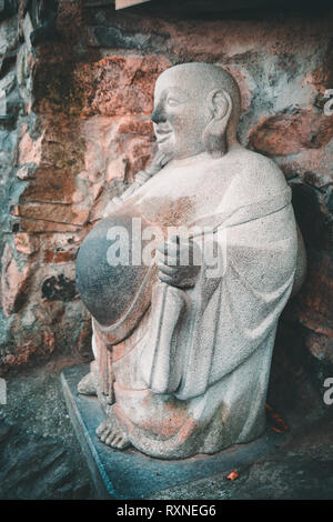 Ancient laughing buddha statue in Yonggungsa Buddhist temple in Busan, South Korea Stock Photo