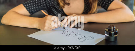 Calligrapher Young Woman writes phrase on white paper. Dream big, set goal, take an action. Inscribing ornamental decorated letters. Calligraphy Stock Photo