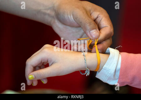 Tibetan monk while putting bracelet on buddihst hand detail Stock Photo