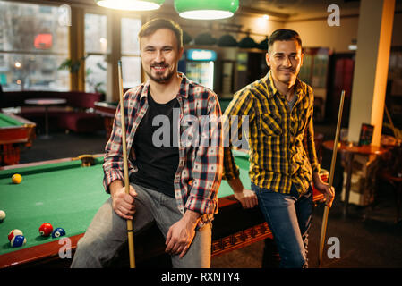 Two male billiard players with cues poses Stock Photo