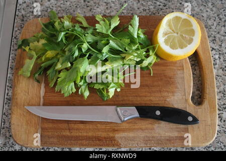 tuft of green garden parsley with lemon lay on kitchen board for cooking