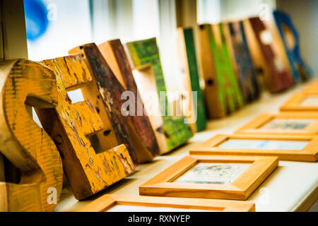 Weathered, colourfully painted wooden letters stand lined up on a windowsill at the Kavaliershaus hotel in Fincken, Röbel-Müritz, Germany. Small framed pictures lie beside them. Stock Photo