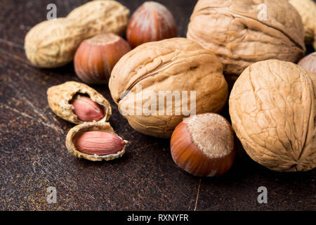 Bunch of nuts in shell and peeled on a dark background. Walnuts, hazelnuts and peanuts. Tasty healthy snack, food Stock Photo