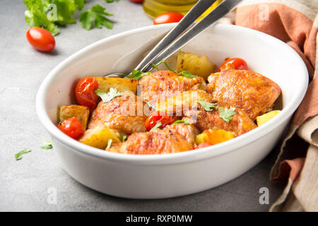 Baked chicken thighs (legs) with crispy crust, potatoes and cherry tomatoes. Simple delicious homemade dinner, traditional meal. Everyday food cooked  Stock Photo