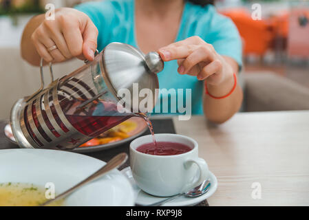 woman hands close up pouring fruit tea from kettle. french press Stock Photo