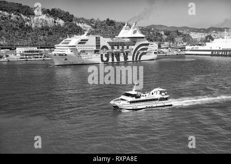 Barcelona, Spain - March 30, 2016: big and small ships or boats marine vessels enter port on blue sea water along beautiful green coast on natural background Stock Photo