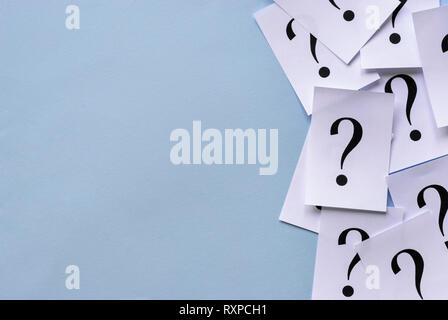Side border of printed question marks on loose sheets of white paper overlaid together with lateral copy space on a blue background Stock Photo