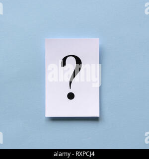 Single black printed question mark on a white card or sign with three dimensional shadow over a blue background in square format Stock Photo