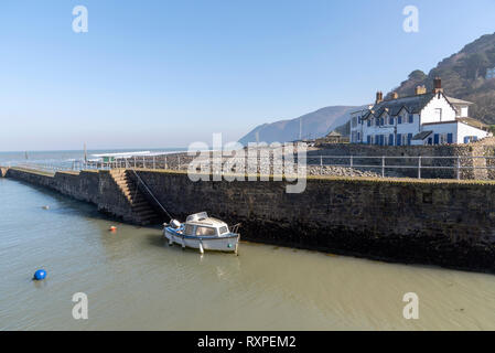 Lynmouth, North Devon, England, UK. March 2019. Lynmouth pier and a  small boat on the West Lyn River  where it meets the Bristol Channel. Stock Photo