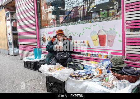 A street scene in Jackson Heights Queens, New York featuring a women selling knick knacks & clothing while talking on her cell phone. On 82nd Street. Stock Photo