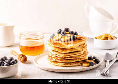 Pancakes with banana,  blueberries on white plate, selective focus. Stock Photo