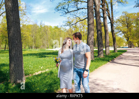 Pregnant woman with husband in park in sunny day Stock Photo