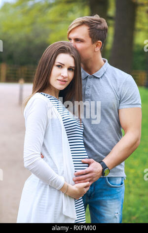 Portrait of lovely future parents in sunny day in park Stock Photo