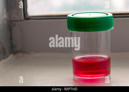 A close up view of a red sterile liqiud in a small plastic bottle with a green lid that is used to clean and steriles medical equipment Stock Photo