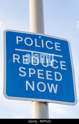 Blue and white pole mounted police reduce speed now sign on the seafront St Annes on Sea Fylde Coast February 2019 Stock Photo