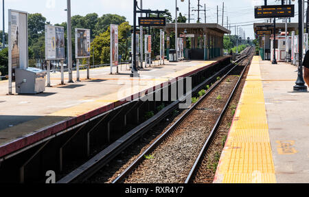 Babylon, New York, USA - 14 August 2018: Looking down the tracks on the platform at the Babylon LIRR station with signs showing the arrival and depart Stock Photo