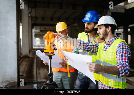 Confident team of architects and engineers working together on construction site Stock Photo