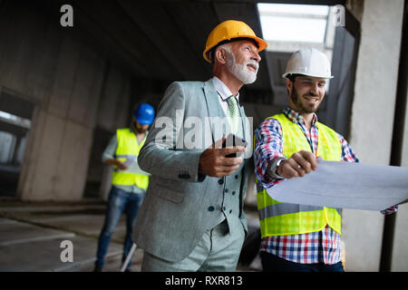 Engineer and construction site manager dealing with blueprints and plans Stock Photo