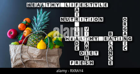 healthy eating wordcloud or crossword with variety of fresh fruits in brown paper bag Stock Photo