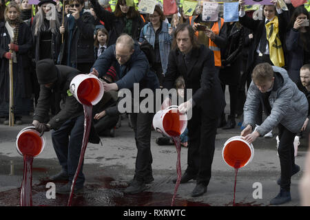 London, Greater London, UK. 9th Mar, 2019. Extinction Rebellion activists.pouring buckets of fake blood outside Downing Street.Hundreds of activists from the Extinction Rebellion climate change movement gathered at Parliament Square, marched to Downing Street, and poured 200 litres of fake blood on the ground. This act of non-violent civil disobedience was carried out to demand from the government direct actions to reduce carbon emissions to zero by 2025, speak the truth about climate change and call for a national citizen's assembly. For the activists, carrying buckets of '' Stock Photo