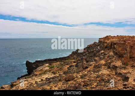 Striking sandy rock formations with black rocks and the ocean in the background at the petrified forest, on the south coast of Australia Stock Photo