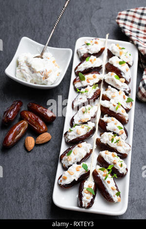 Dates  stuffed with cream cheese and almonds on black stone background Stock Photo