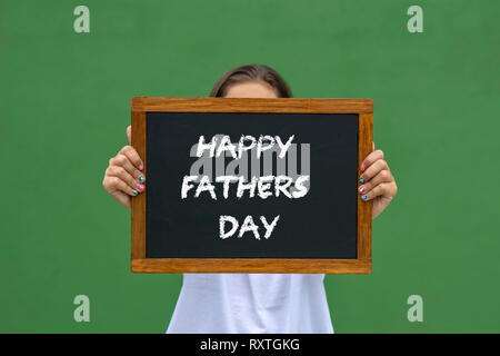 girl holding a blackboard with the message happy fathers day written Stock Photo