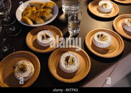 Many delicious hot baked camemberts with sultanas and rosemary on a table Stock Photo