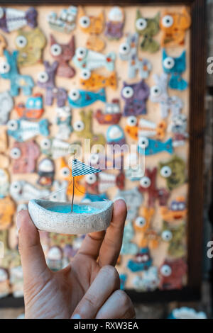 Man's hand holds a toy sailboat with a blue flag Stock Photo
