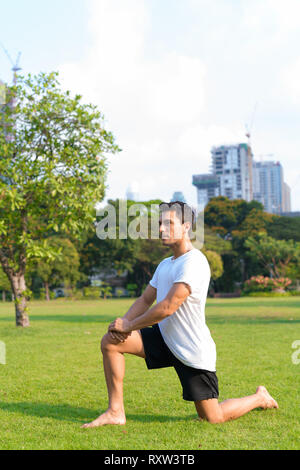 Young handsome Hispanic man doing forward lunge at the park Stock Photo