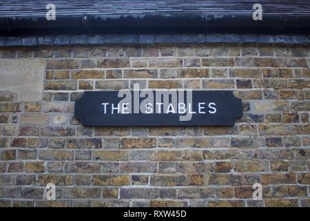 Wooden sign for The Tables with white lettering on black background against a brick wall Stock Photo