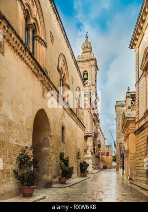 Mdina, Malta: Church of the Annunciation of Our Lady in narrow sett street of medieval town with lantern lights. Medieval Maltese architecture Stock Photo