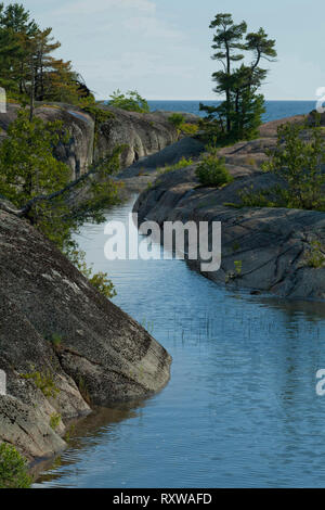Small channel between rocky islands and iconic white pines along the west coast of Phillip Edward Island,Georgian Bay, near Killarny Provincial Park, Ontario, Canada Stock Photo