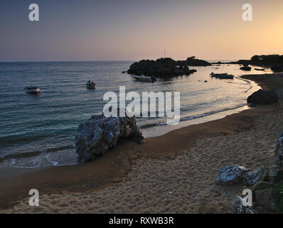 Beautiful sandy beach with rocks in the sea at dusk time, blue hour, Stoupa, Peloponnese, Greece. Stock Photo